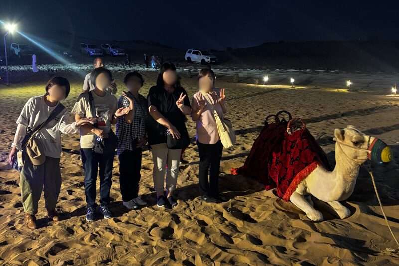 ドバイの砂漠でラクダと写真撮影