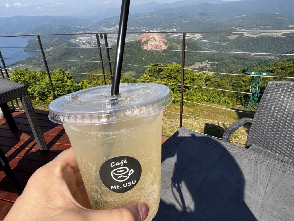 Café Mt.USUのりんごソーダ越しに洞爺湖と昭和新山を見渡す有珠山山頂の景色