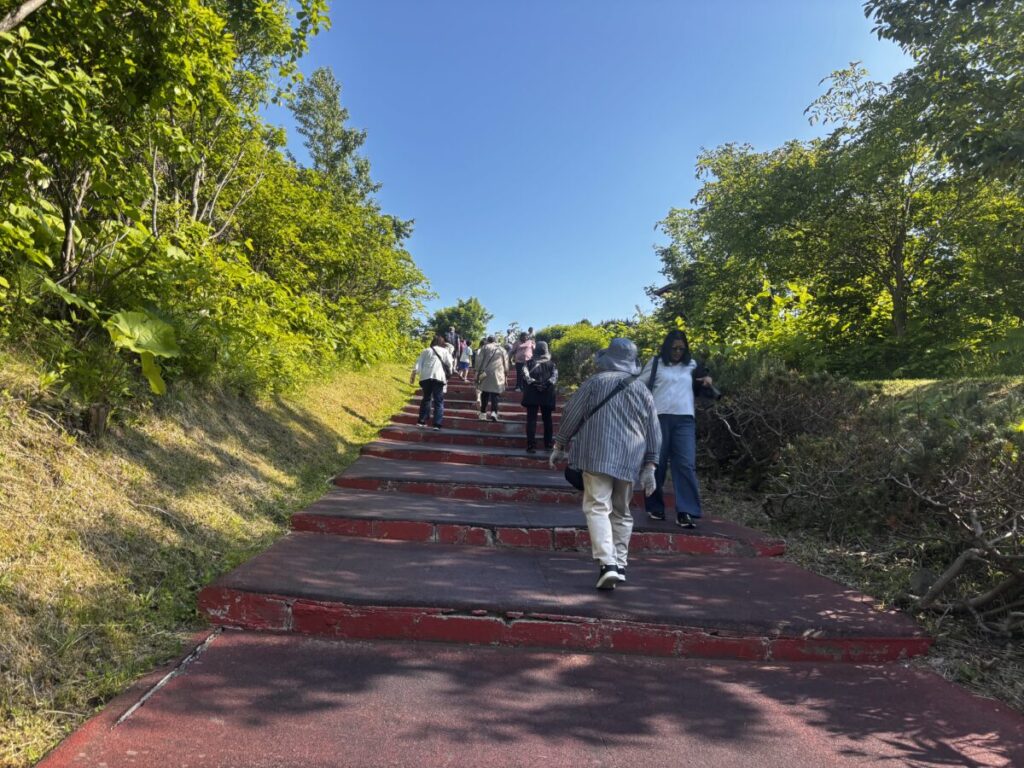 有珠山山頂駅からUSU360展望台へ続く階段の遊歩道を歩く観光客