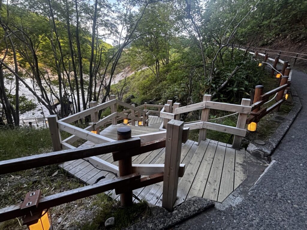 登別地獄谷の遊歩道にある木の階段と、夕方に灯るあんどんの明かり