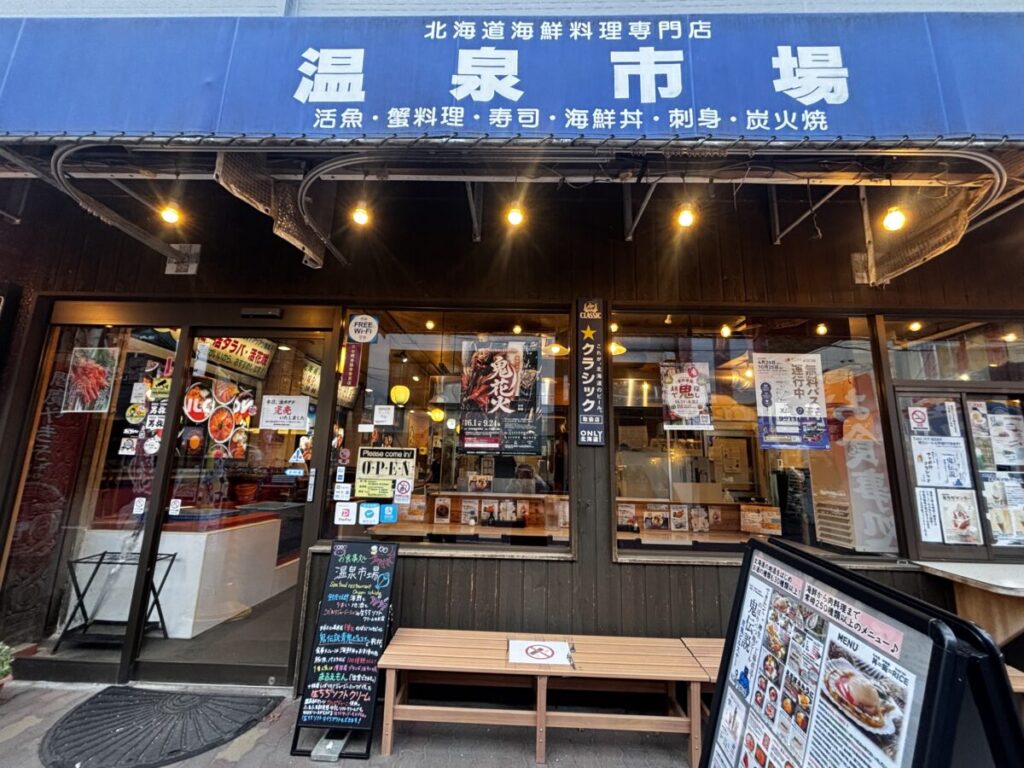 登別温泉街の「温泉市場」外観、海鮮丼や蟹料理を掲げた青い看板