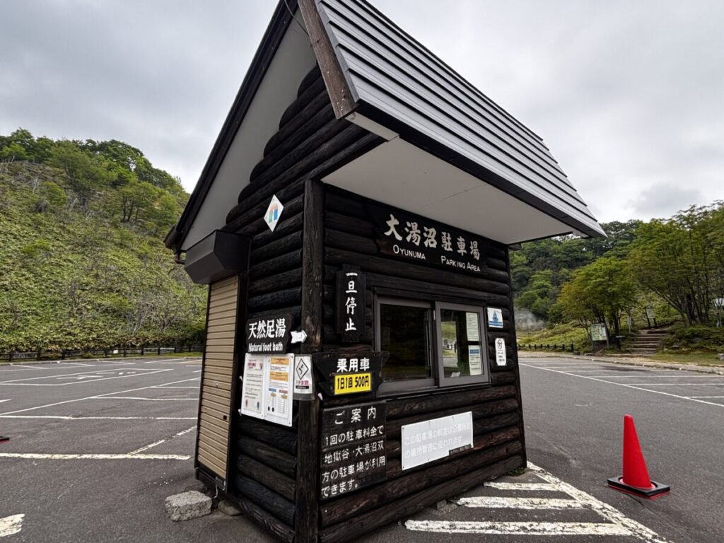 大湯沼駐車場の料金所、乗用車1日1回500円と天然足湯の案内表示