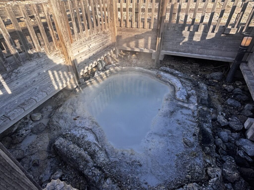 登別地獄谷の鉄泉池、木の柵に囲まれて湯気を上げる灰白色の湯だまり