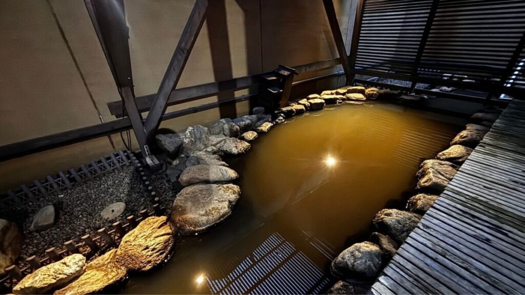 ゆとりろ洞爺湖の露天風呂、薄い茶色に濁った岩風呂とすのこの通路